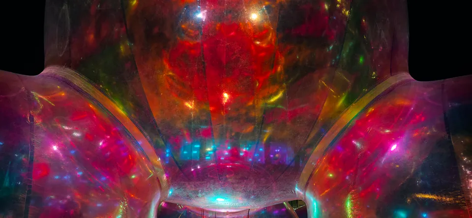 Red, green and blue light reflects inside a large transparent sphere in a close-up night-time view.
