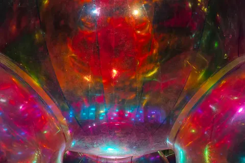 Red, green and blue light reflects inside a large transparent sphere in a close-up night-time view.