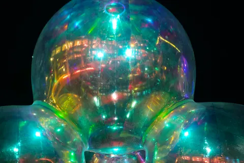 Three large transparent spheres reflect colourful lights against a dark sky with a lit building behind.
