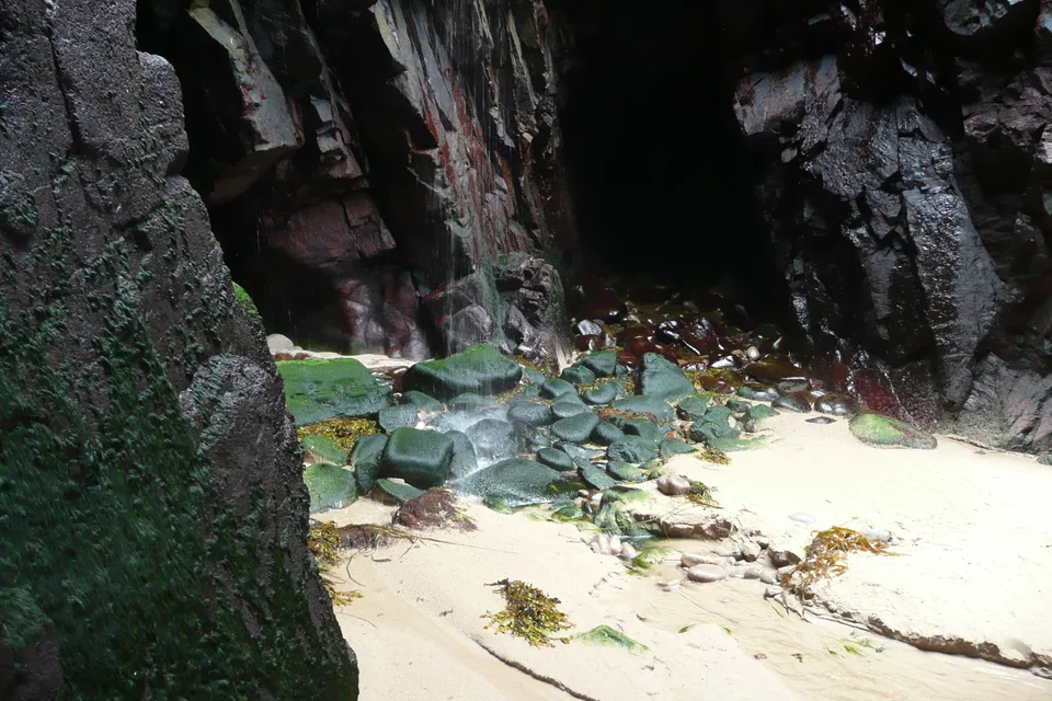 A waterfall falling from the cliffs onto Plémont beach in Jersey