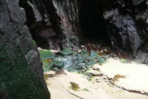 A waterfall falling from the cliffs onto Plémont beach in Jersey